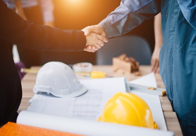 Commercial Contractors in Central Illinois shaking hands over a blueprint for a new construction project