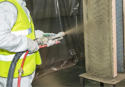 Commercial builder applying spray fireproofing to a structure's main steel beams