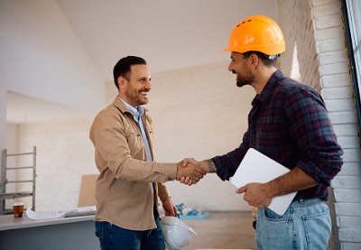 Two men shake hands at the site of a commercial renovation. Mid-Illinois Companies does commercial remodeling in Macomb IL.